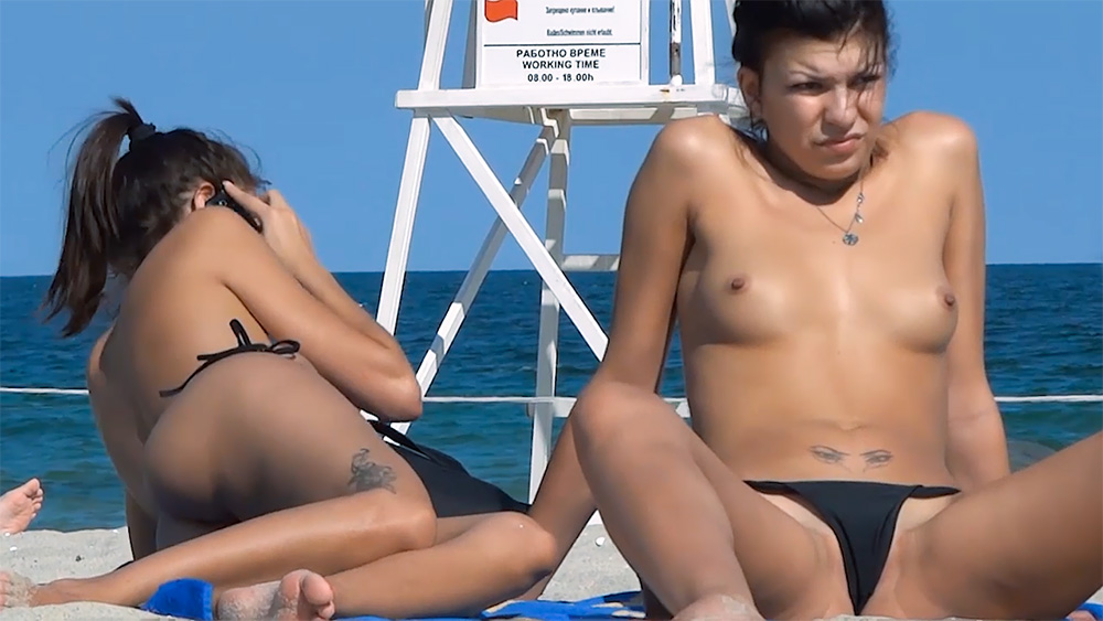 Two Women Topless on the Beach in Black Bikini Bottoms