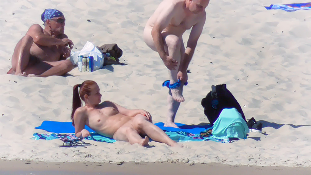 Odpočinek na modrém ručníku na nudistické pláži
