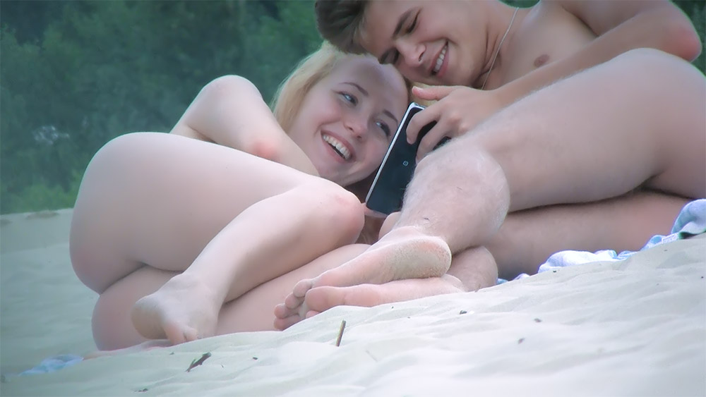 Nude Beach Couple Laughing Over a Mobile Phone