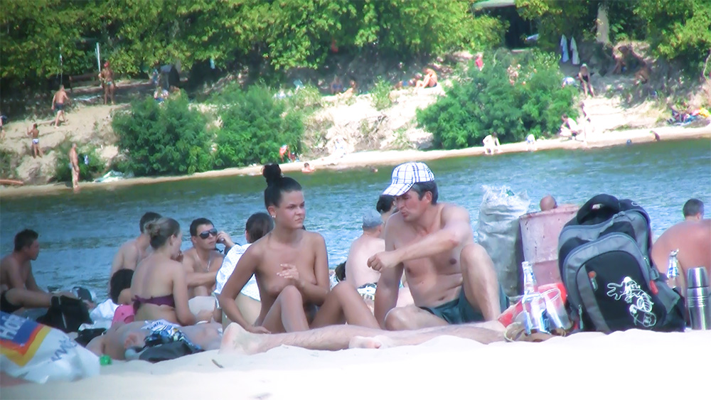 Six Nudists Gathered on the Shore by Calm Water