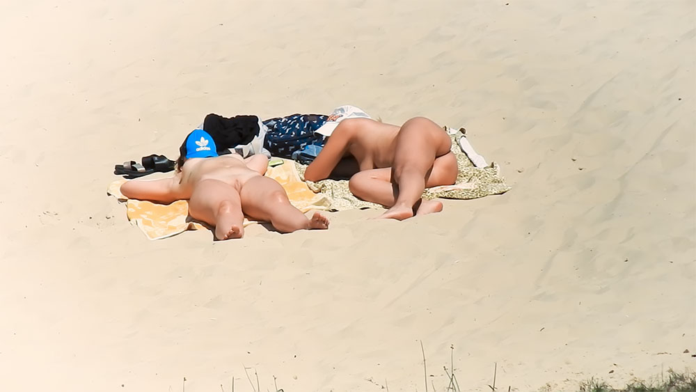Two Nude Beach Sunbathers Resting on a Yellow Towel