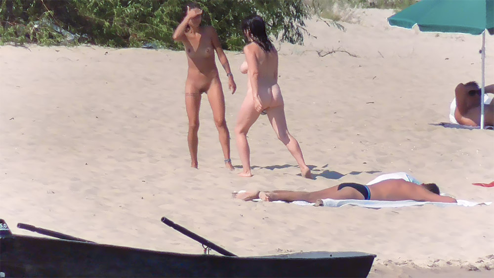 Sandy Nude Beach with Two Nudists Near the Trees