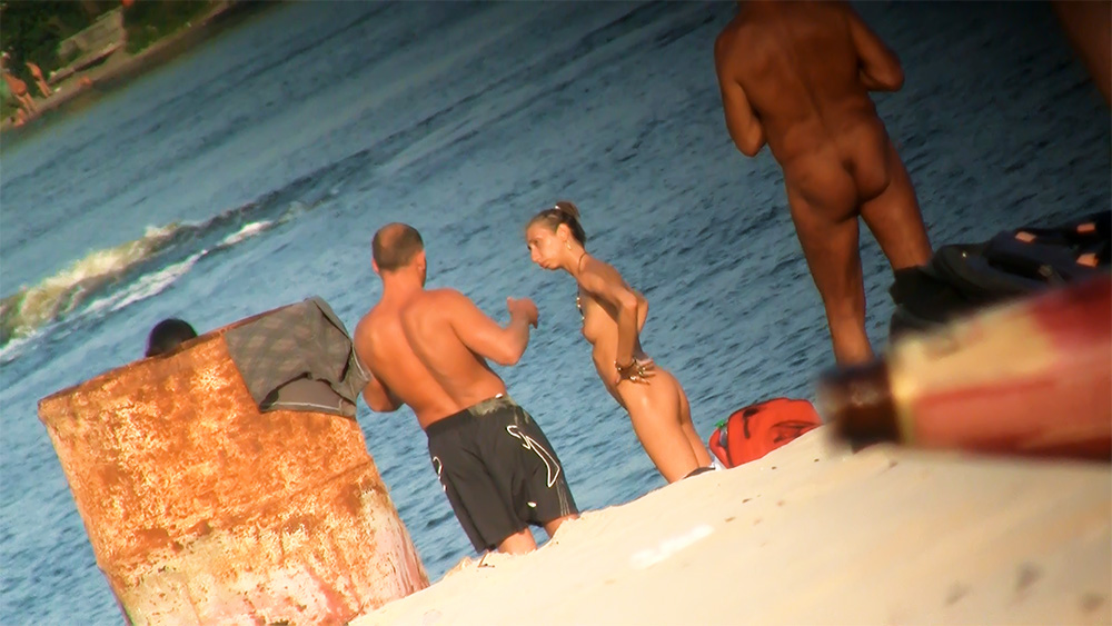 Three Nudists Gathering on a Sandy Shore