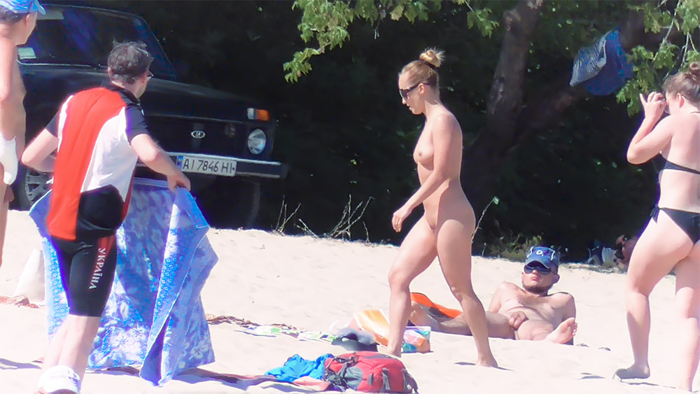Walking Past a Seated Sunbather on a Nude Beach