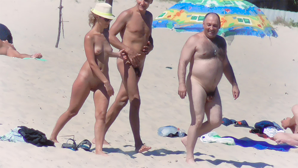 Three Nudists Gathered on Bright Beach Sand