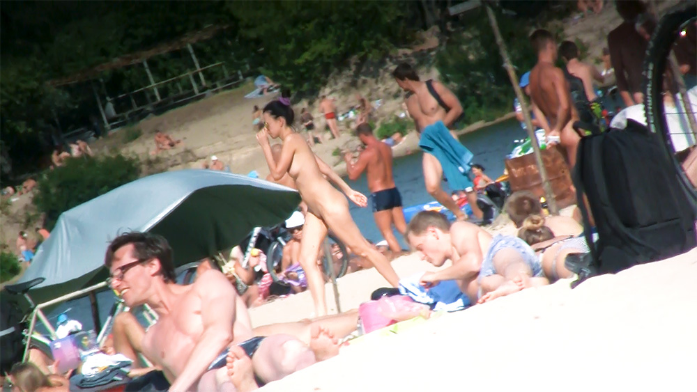 Naturisti riuniti su un'affollata spiaggia naturista di ciottoli