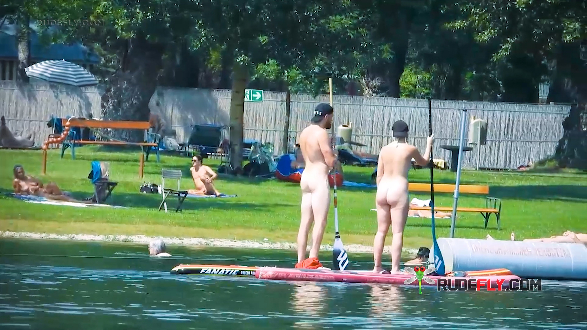 Paddleboarding Naturists Crossing a Calm Lake Swim Area