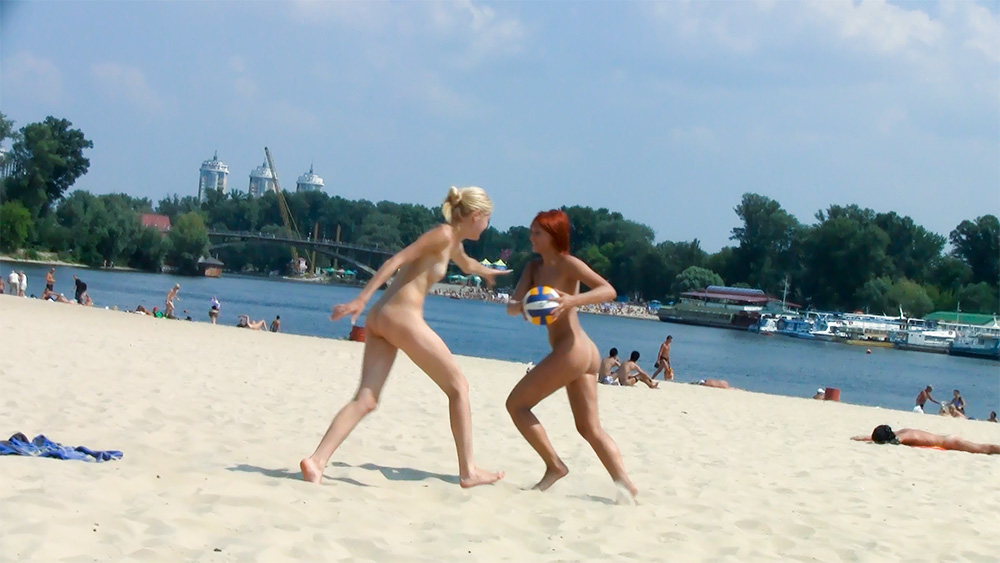 Two Nudists Tossing a Volleyball by the River