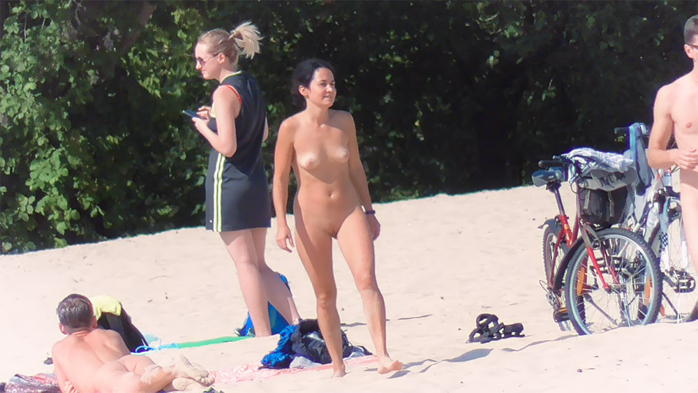 Four Nudists Mingling on Sand Near the Waterline