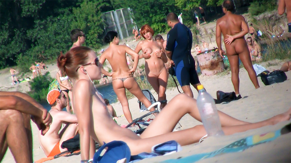 Six Naturists Mingling Near a Foreground Water Bottle