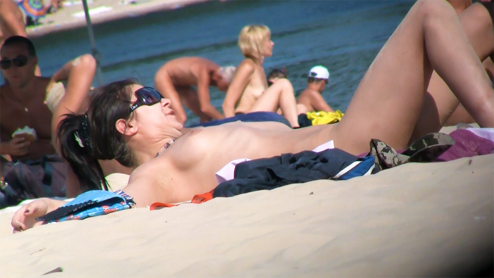 Sunbathing and Standing by the Shore at a Nudist Beach