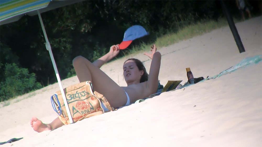 One Woman Topless on Beach Beside a Burlap Sack Bag