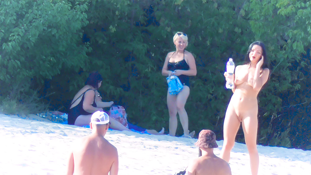 Chwila na piaszczystej plaży dla nudystów z butelką wody