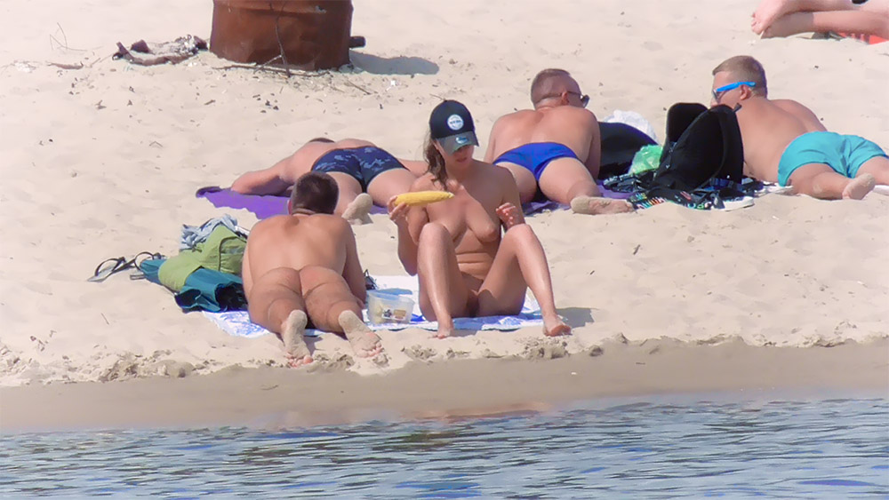 Vier Nudisten entspannen zusammen an einem Sandstrand