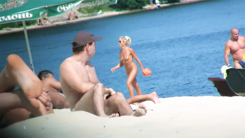 Due nudisti sulla riva con un pallone da spiaggia