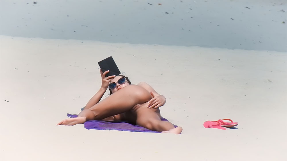 Reading a Tablet on a Purple Towel at a Nude Beach
