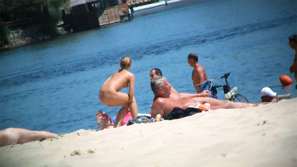 Five Nudists Gathered on a Sunny Riverbank Beach