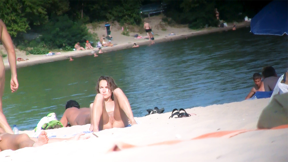 Brunette Nudist Resting on Elbows by the Shore