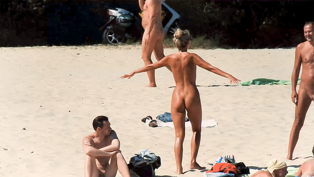 Čtyři nudisté tráví čas na sluncem ozářeném písku