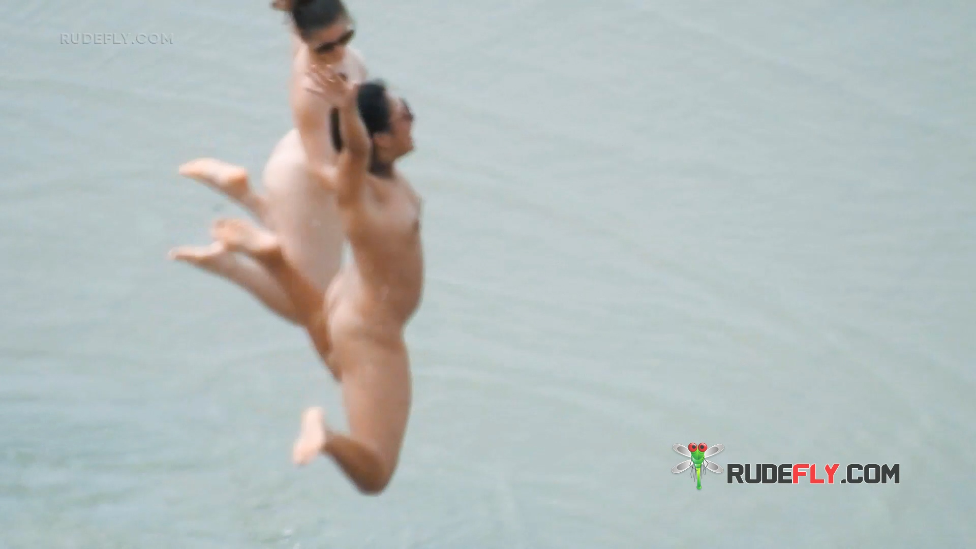Two Nudists Caught Mid-Jump Above a Lake