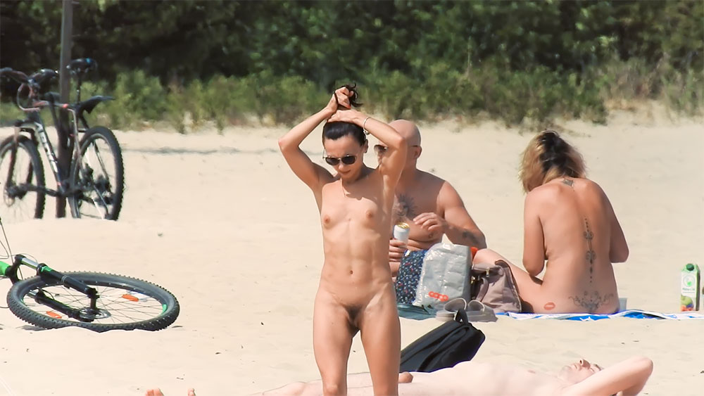 Three Nudists Settling near a Blue Beach Umbrella
