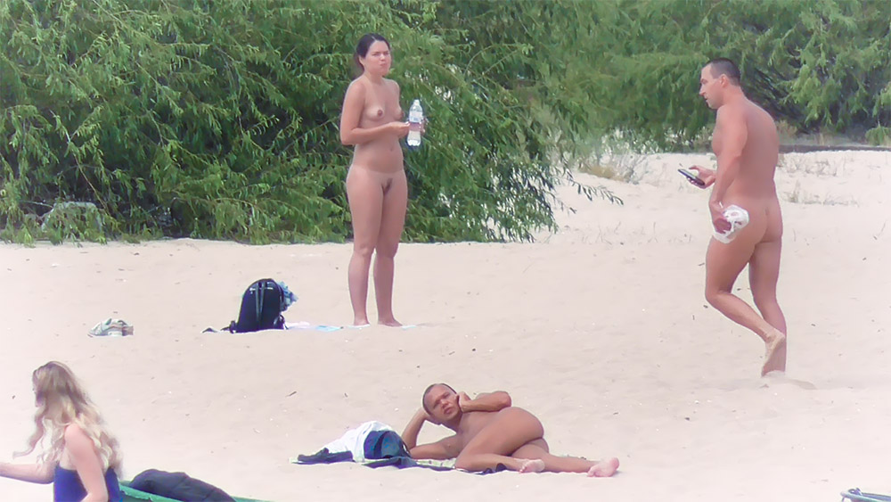 One Woman at the Nudist Beach Beside a Blue Backpack