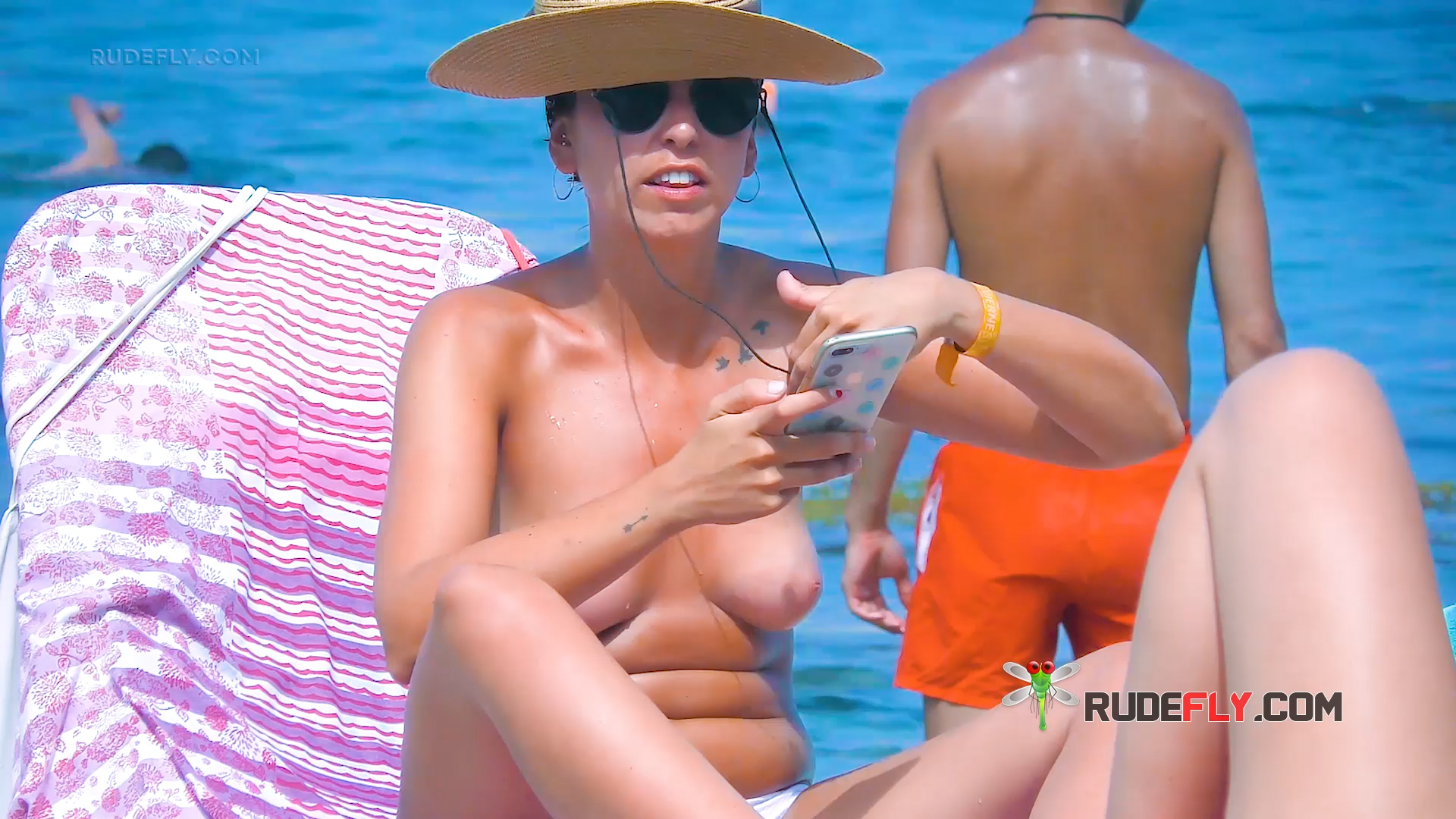 Three Adults Relaxing Topless on Beach