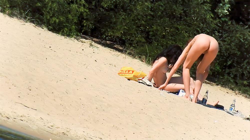 Two Nudists Arranging Items Beside a Yellow Bag