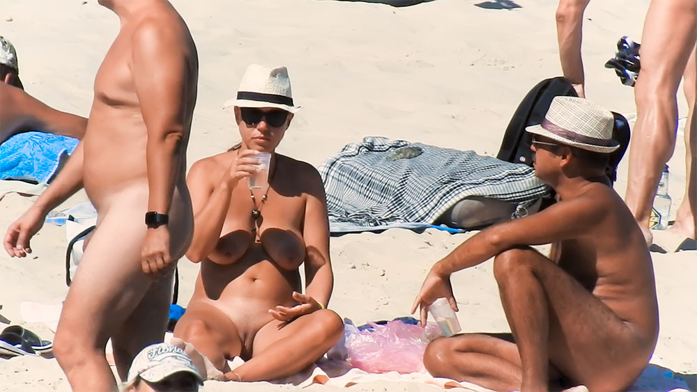 Nude beach girl sunbathes next to her man outdoors 2