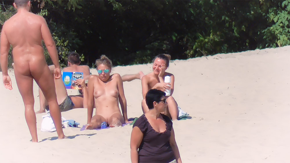 Tři ženy odpočívající na slunečné toplessové pláži