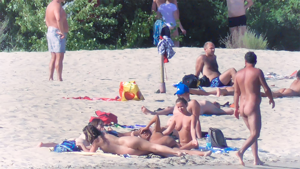 Four Nudists Resting on the Sand Near a Beach Ball