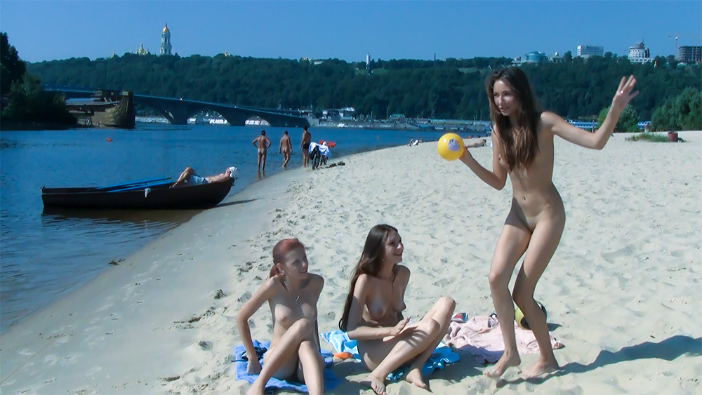 Three Nudists Gathered on a Riverbank Beach Towel