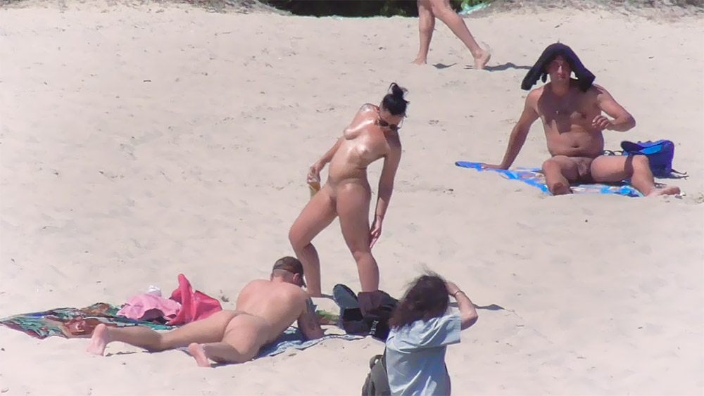 Nakładanie kremu z filtrem na stojąco na plaży dla nudystów