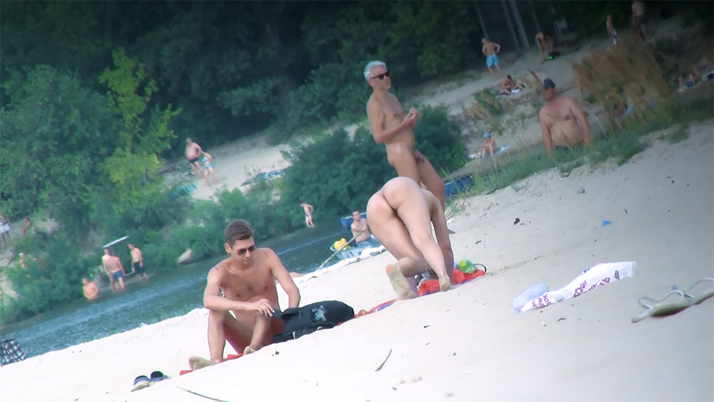 Písečná nudistická pláž s koupající se, která se stará o plážové hračky