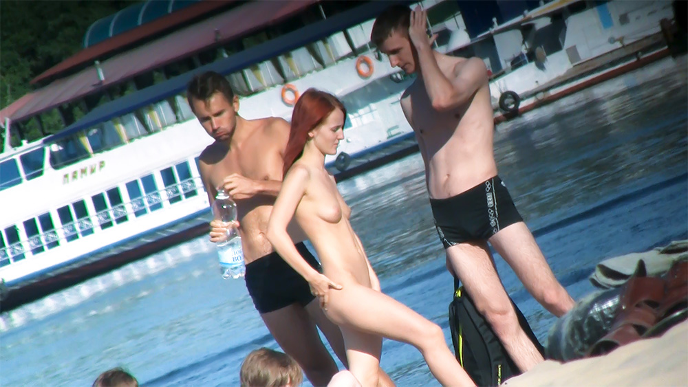 Applying Lotion at the Shoreline on a Nude Beach