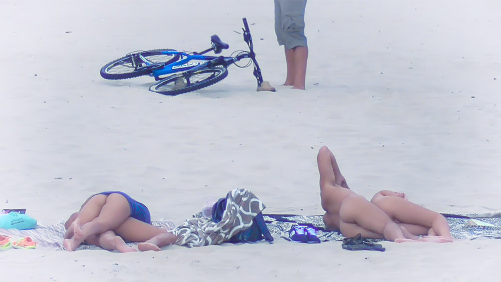 One Woman Topless on a Beach Towel in Blue Bottoms