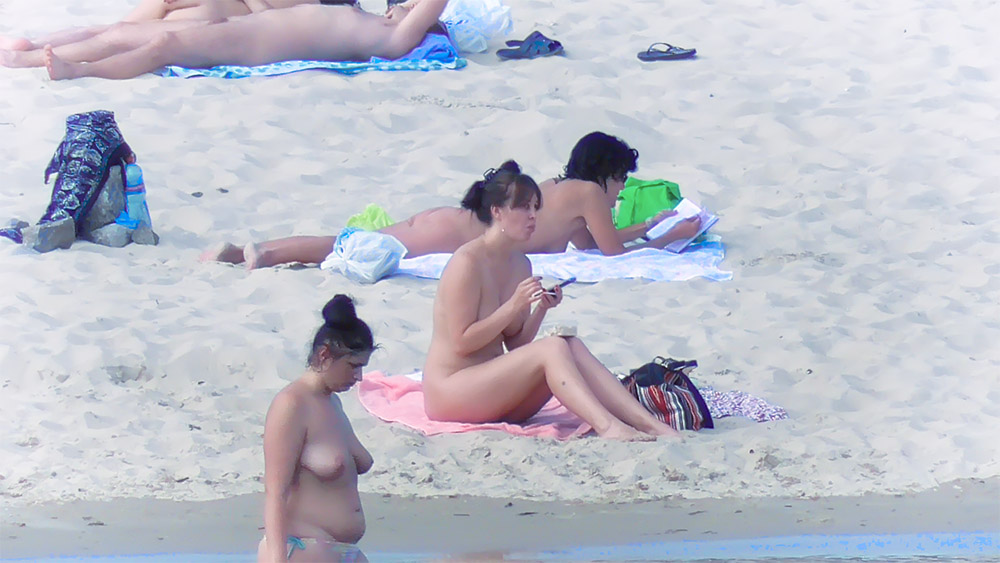 Čtyři nudisté odpočívají na ručnících u břehu