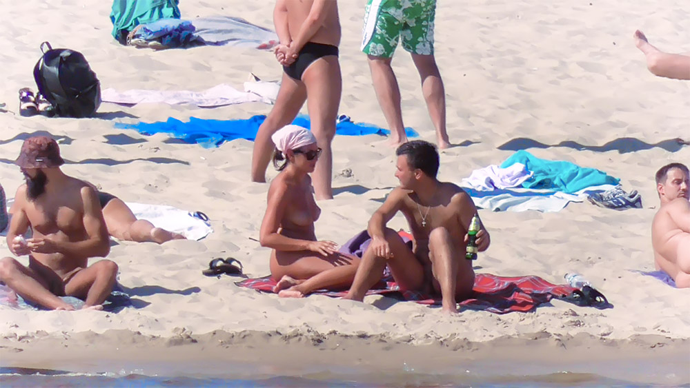 Two Nudists Chatting on a Red Beach Towel
