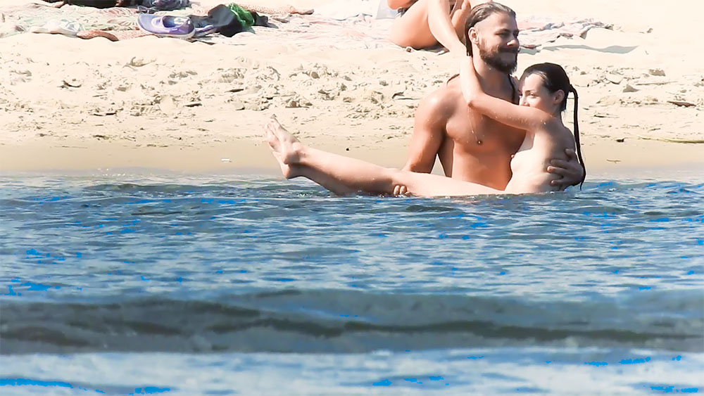 Nude Beach Couple Sitting Together in the Surf