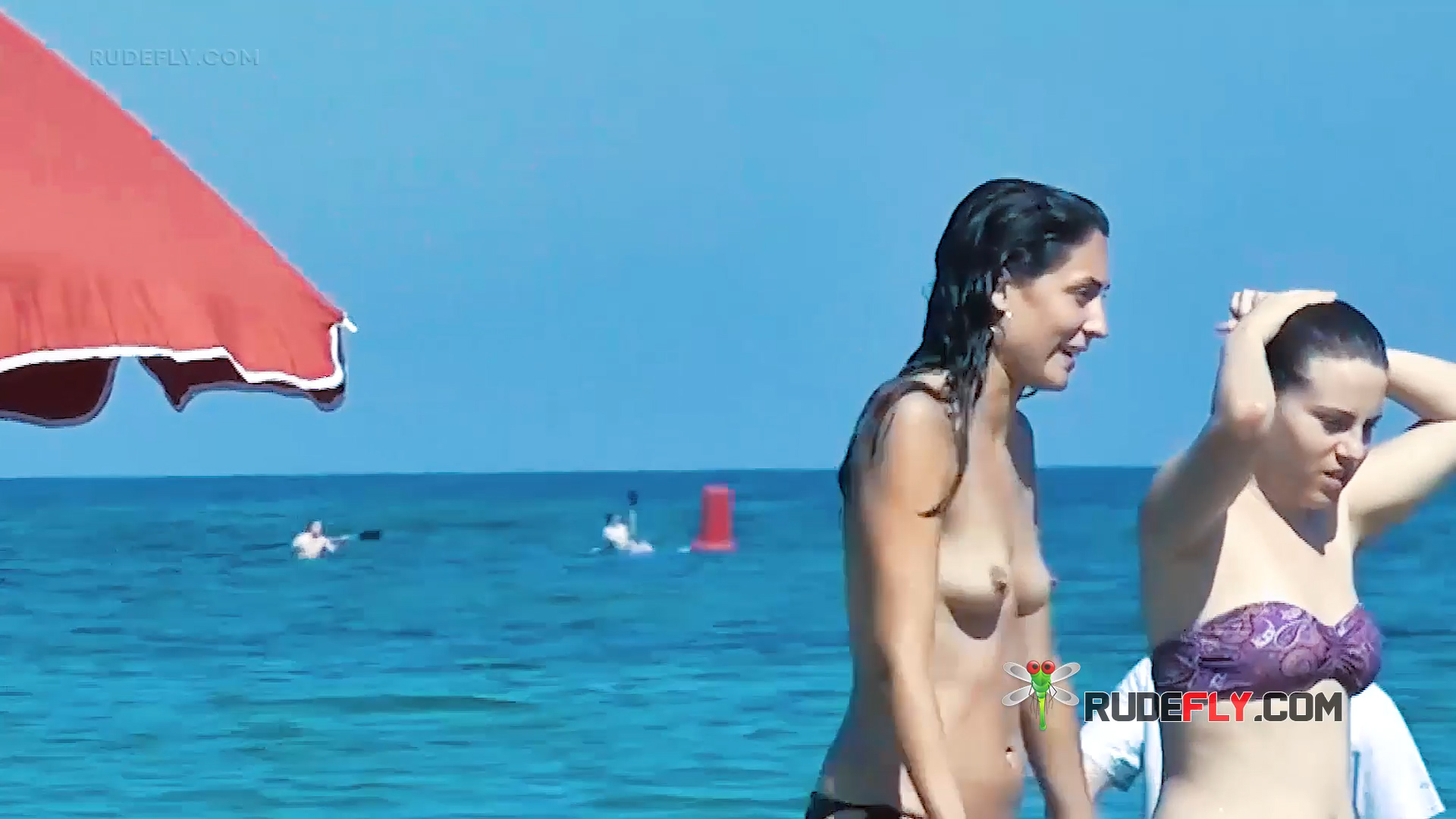 Two Brunette Women Topless on a Sunny Beach