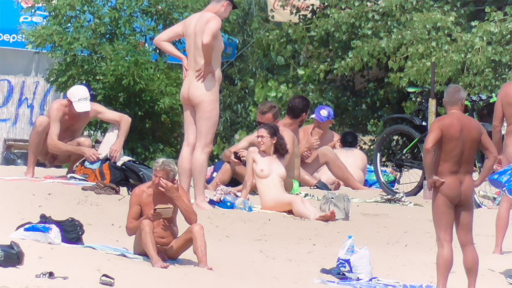 Woman with Glasses Seated Among Nude Beach Bathers