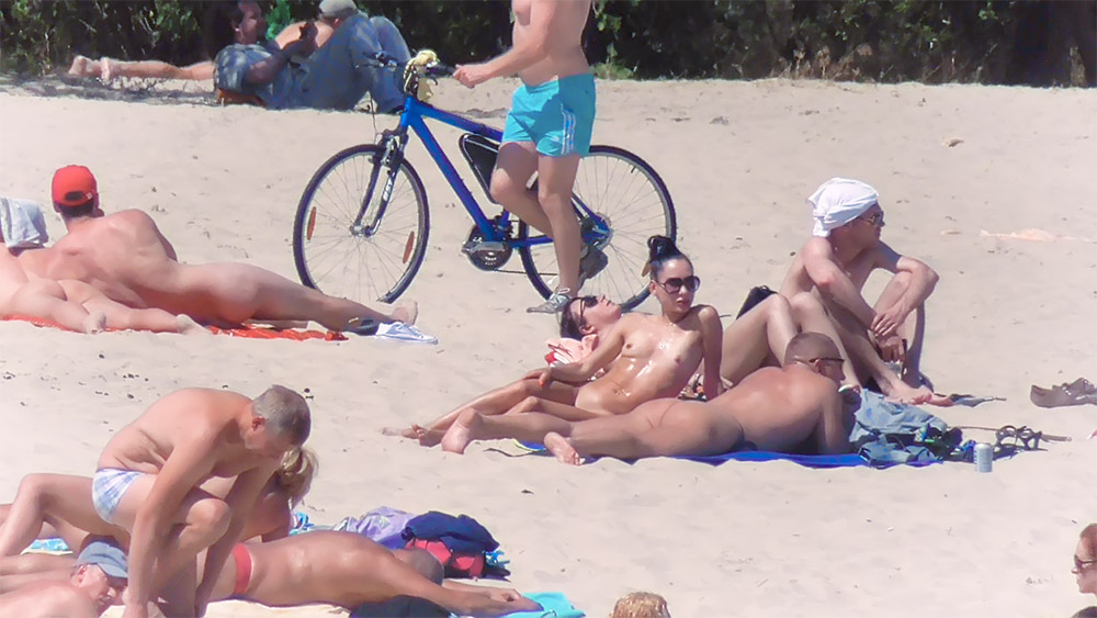 Drie naturisten rusten samen op een open strand