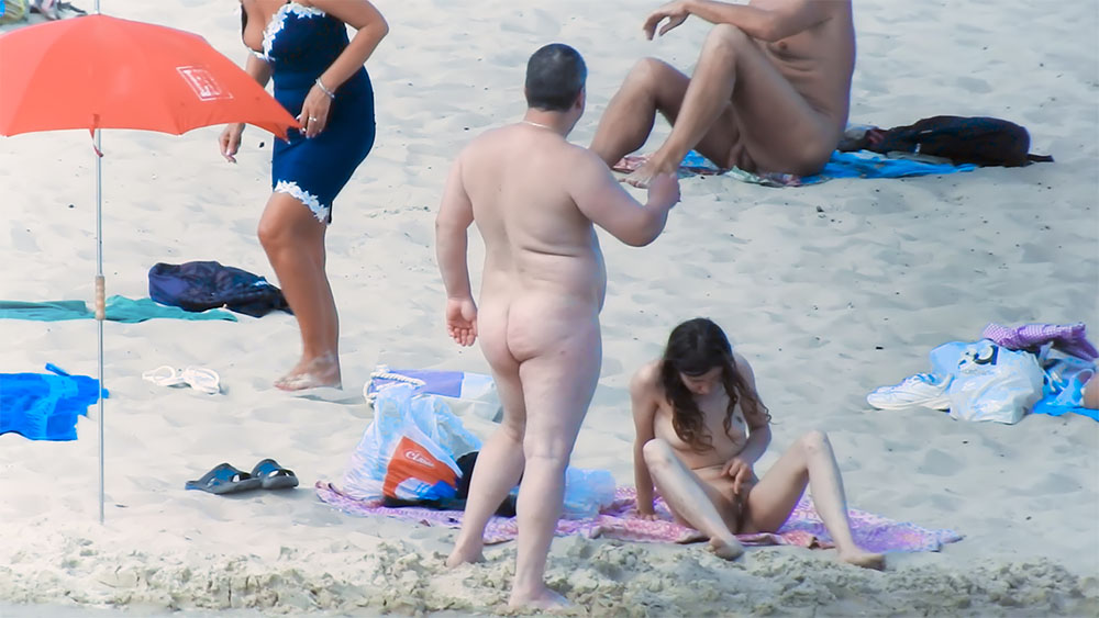 Sezení na vzorované osušce na nudistické pláži