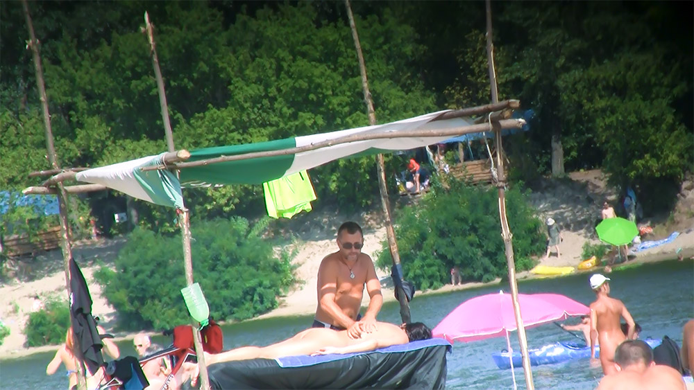 Two Naturists on a Floating Platform by the Shore