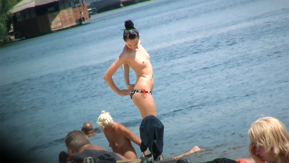 One Topless Woman Standing by the Calm Shoreline