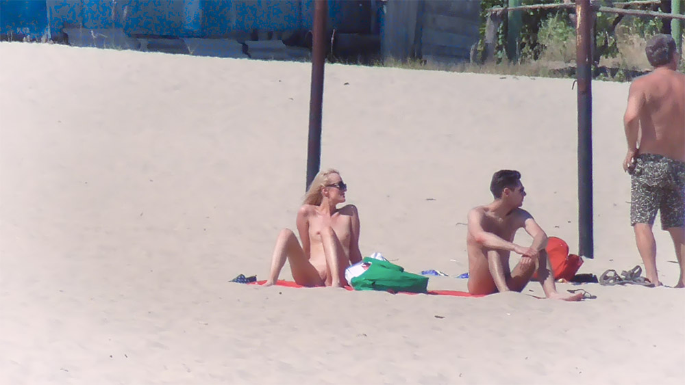 Miejsce na plaży dla nudystów z czerwonym ręcznikiem i zielonym materiałem