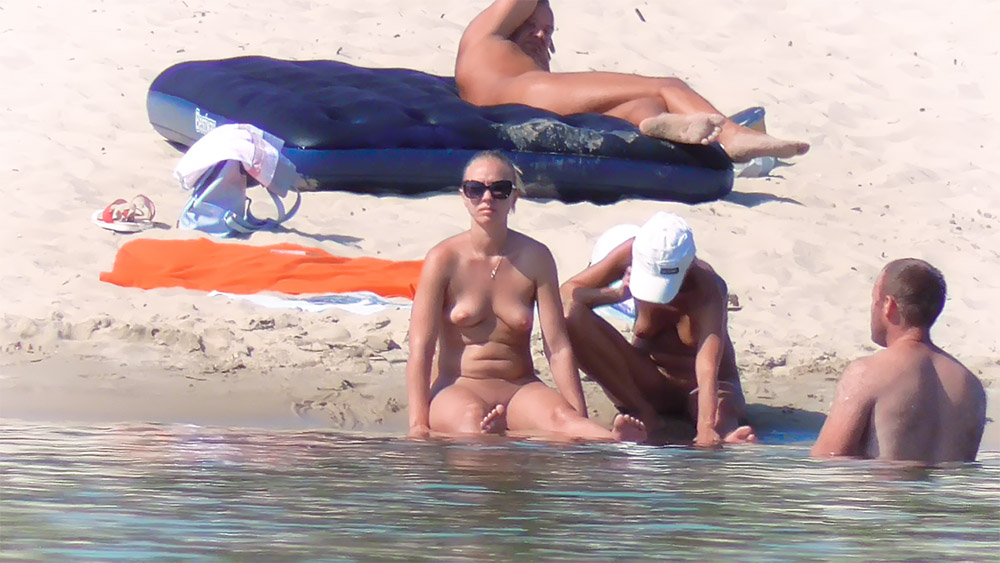 Twee naturisten rustend waar het zand het water raakt