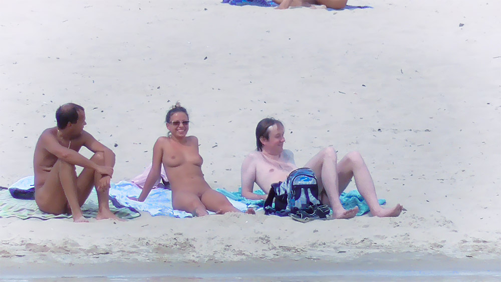 Two Nudists Sunbathing on a Sandy Shore