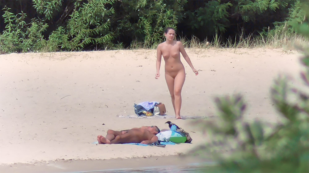 Drie naturisten verspreid over een rustig zandstrand