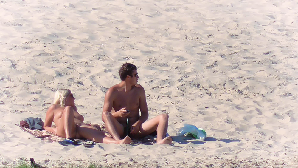 Para na plaży nudystów odpoczywająca na piasku przy brzegu